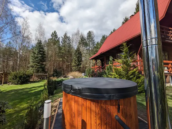 Domek z balią w lesie — ruska bania z jacuzzi na tle drewnianej chaty In The Woods, Puszcza Knyszyńska