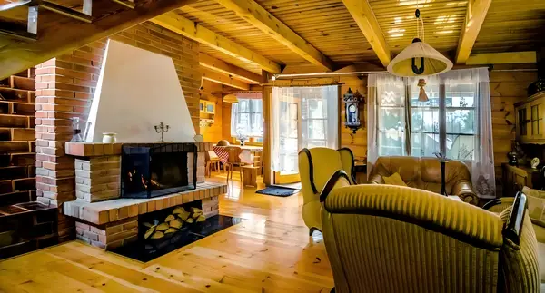 In The Woods Supraśl — panorama salonu z fotelem i kominkiem